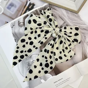 Detailed close-up of a large dalmatian print bow hair clip with pearl embellishment.