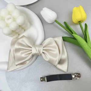 Detailed view of champagne satin bow hair clip with silver-tone metal barrette mechanism