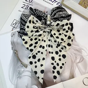 Detailed view of a black and white patterned bow hair clip with elegant pearl accents.