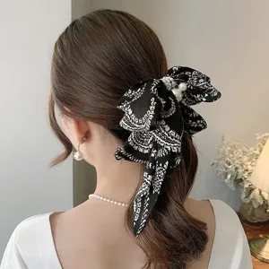 Close-up view of a vintage black patterned bow hair clip with pearl accents on a model.