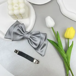 Detailed view showing the elegant grey satin bow hair clip and its black spring base mechanism