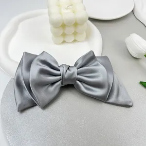 Elegant grey satin bow hair clip with luxury smooth texture and minimalist design detail.