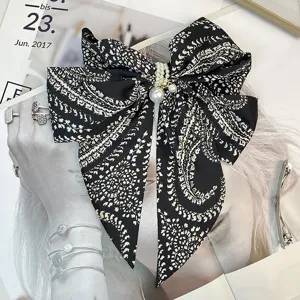Detailed view of vintage black patterned satin bow hair clip with pearl embellishments