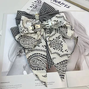Detailed back view of a vintage houndstooth and paisley satin bow hair clip with pearls