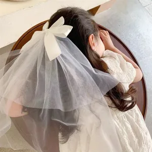 Detailed view of a sweet white bow hair clip with a layered mesh veil on a young girl