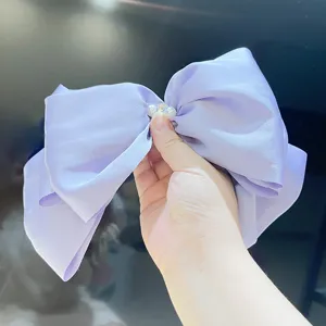 Detailed close-up of a large lavender pearl satin bow hair clip with pearl rhinestone center