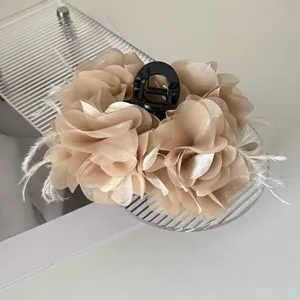 Macro-opname van een beige stoffen bloem haarclip met delicate witte veeraccenten.