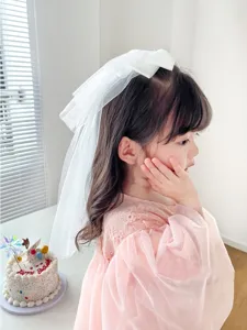 Detailed side view of a young girl wearing a white bow hair veil accessory for flower girls