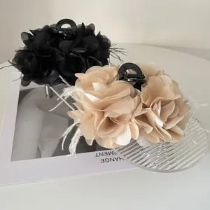 Detail van elegante stoffen bloem haarklemmen met veeraccenten in zwart en beige.