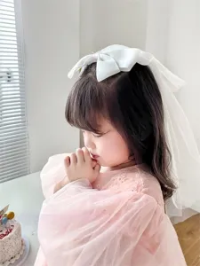 Detailed side view of a young girl wearing a delicate white mesh bow hair veil hairclip
