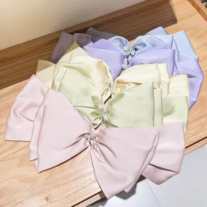 Detailed view of oversized pearlescent satin French hair bows with pearl and rhinestone
