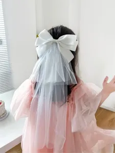 Detailed back view of a white bow hair clip with a layered tulle veil on a young girl