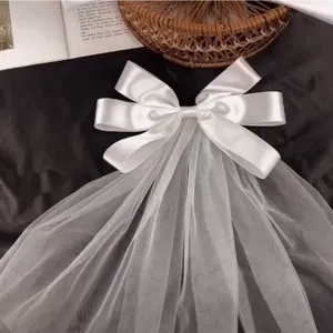 Detail view of a white satin bow with ethereal tulle veil for girls' hair accessory