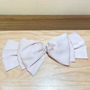 Detail of oversized pearl pink satin bow hair clip with rhinestones and pearls