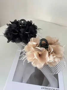 Detailweergave van zwarte en champagne stoffen bloem haarklemmen met veren accenten