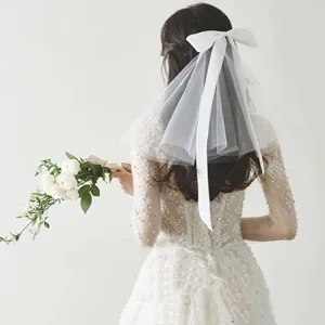 Elegant white bow mesh veil hair accessory shown on the back of a flower girl head