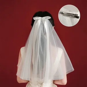 Back view of elegant white bow veil for girls including metal hair clip detail