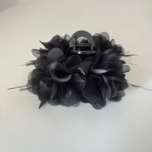 Gedetailleerd overzicht van een elegante zwarte stoffen bloemenhaarklem met veren