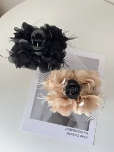 Gedetailleerde macro-opname van elegante stoffen bloem haarklem met zachte veren