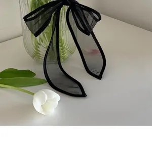 Gedetailleerde close-up van zwarte organza mesh strik haarwokkels met elegante textuur