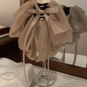 Κοντινό πλάνο με κομψό μπεζ κλαμερ μαλλιών με τούλινο φιόγκο και παγιέτες