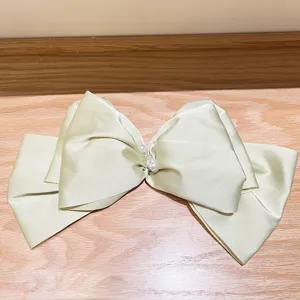 Detailed view of a large pearlescent satin French bow hair clip with pearl accents.