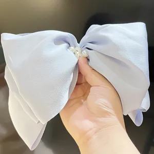 Detailed view of light blue satin bow hair clip with pearl and rhinestone center