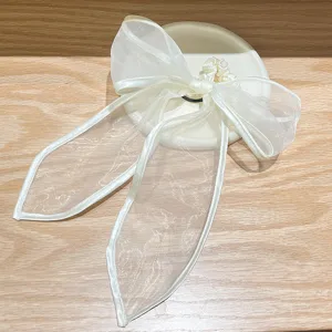 Close-up detail van een delicate witte organza haarstrik met elegante lange slierten.