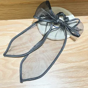 Detailweergave van de zwarte organza strik scrunchie met fijne stoftextuur en glans