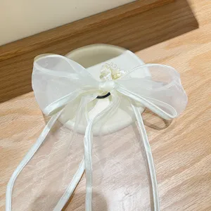 Detailopname van een witte organza strik haarelastiek op een houten ondergrond