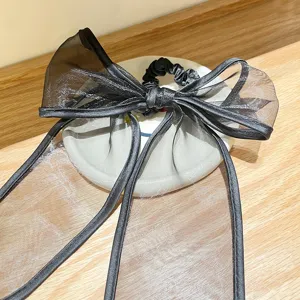 Detailopname van een elegante zwarte organza strik haarelastiek op een wit schoteltje
