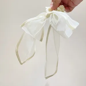 Detail van een elegante witte organza strik haarelastiek met lange vloeiende linten