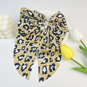 Detailed view of a leopard print satin bow hair clip with elegant pearl accents.