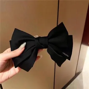 Detalle de un gran pasador para el pelo con lazo de satén negro de tres capas