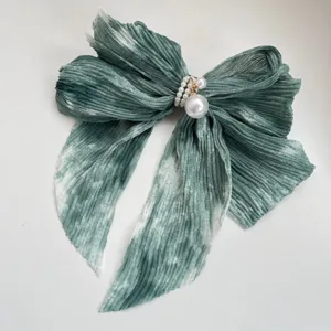 Détail d'une barrette à nœud en mousseline plissée avec dégradé coucher de soleil et perles