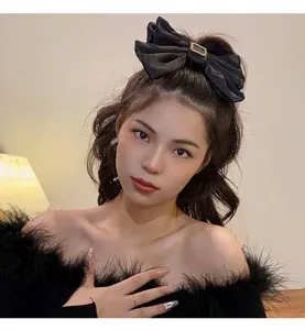 Elegant large black satin bow hair clip with rhinestone buckle detail on a female model.