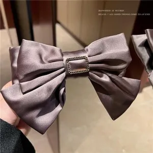 Detailed macro view of a dark mauve satin bow hair clip with a gold-tone square buckle
