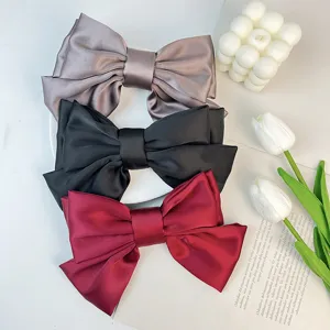 Close-up of three-layer satin bow hair clips in grey, black, and red