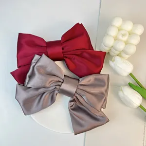 Close-up of elegant red and taupe satin bow hair clips with soft fabric texture