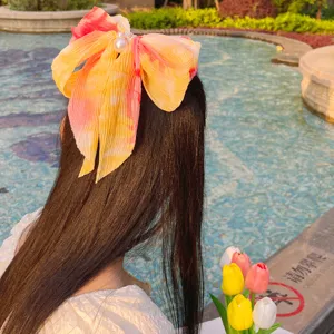 Détail d'une pince à cheveux nœud en mousseline plissée tie-dye soleil avec perles