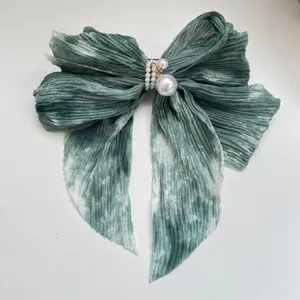 Vue détaillée d'une pince à cheveux nœud en mousseline plissée verte avec des perles