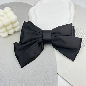 Close-up of a elegant large black satin bow hair clip with a smooth ribbon texture