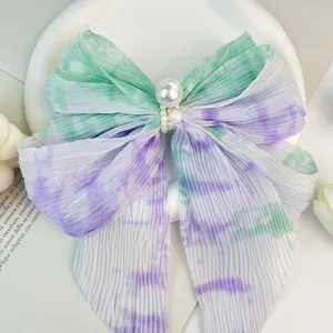 Détail d'un nœud papillon en mousseline plissée avec dégradé tie-dye et perles