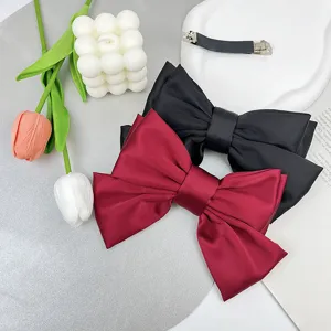 Detail view of elegant three-layer satin bow hair clips in burgundy and black colors