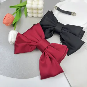 Detail of wine red and black satin three-layer bow hair clips with elegant lifestyle props.