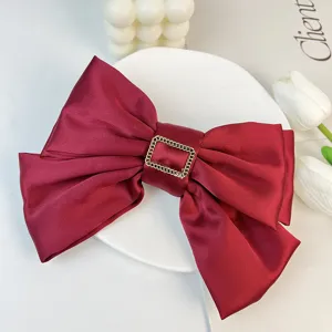 Close-up of elegant burgundy satin three-layer bow hair clip with gold metal buckle