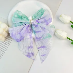 Détail d'une pince à cheveux en mousseline plissée avec dégradé et perle