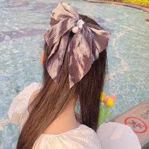 Vue de dos d'une fille avec une barrette à nœud en mousseline dégradé et perles.