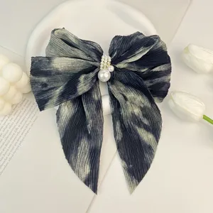 Gros plan d'un nœud en mousseline de soie plissée tie-dye avec embellissement de perles