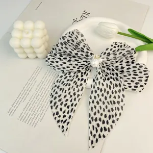 Détail d'une pince à cheveux en mousseline plissée avec perles et motif animal